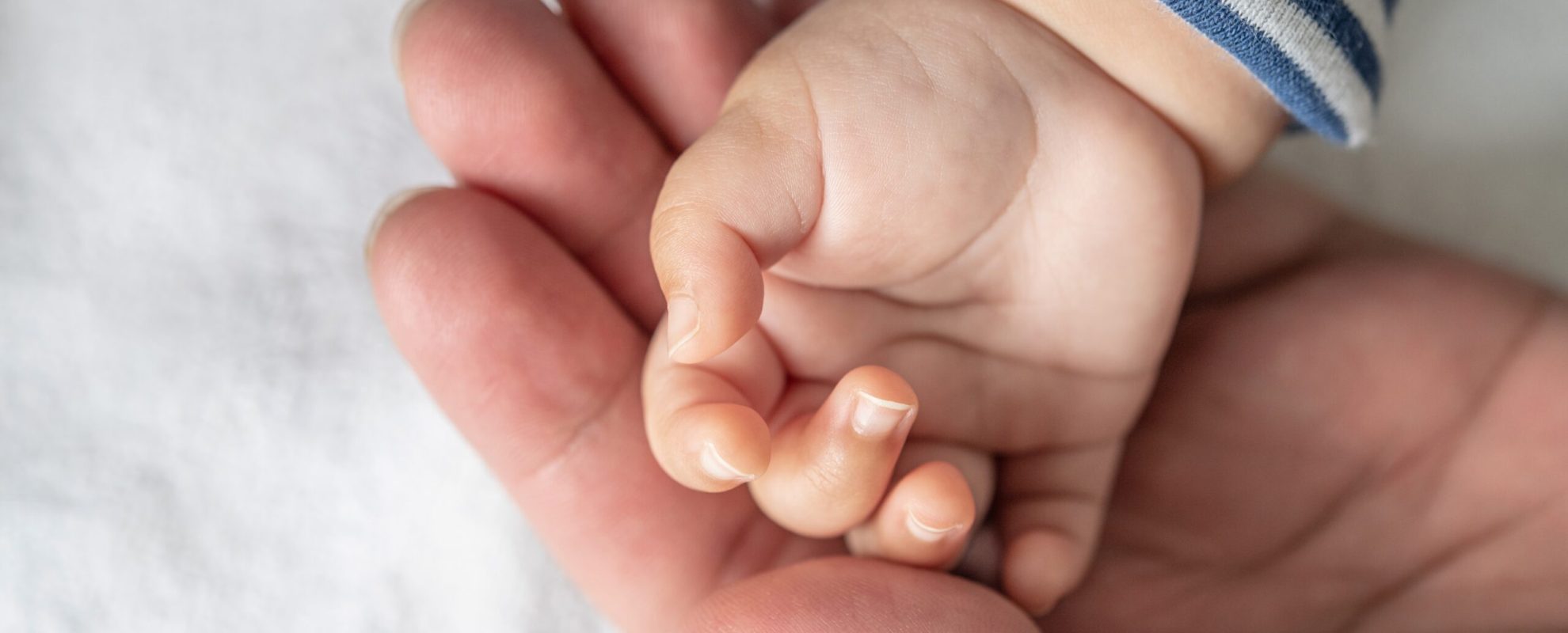 Newborn baby hand in white bed. Selective focus.