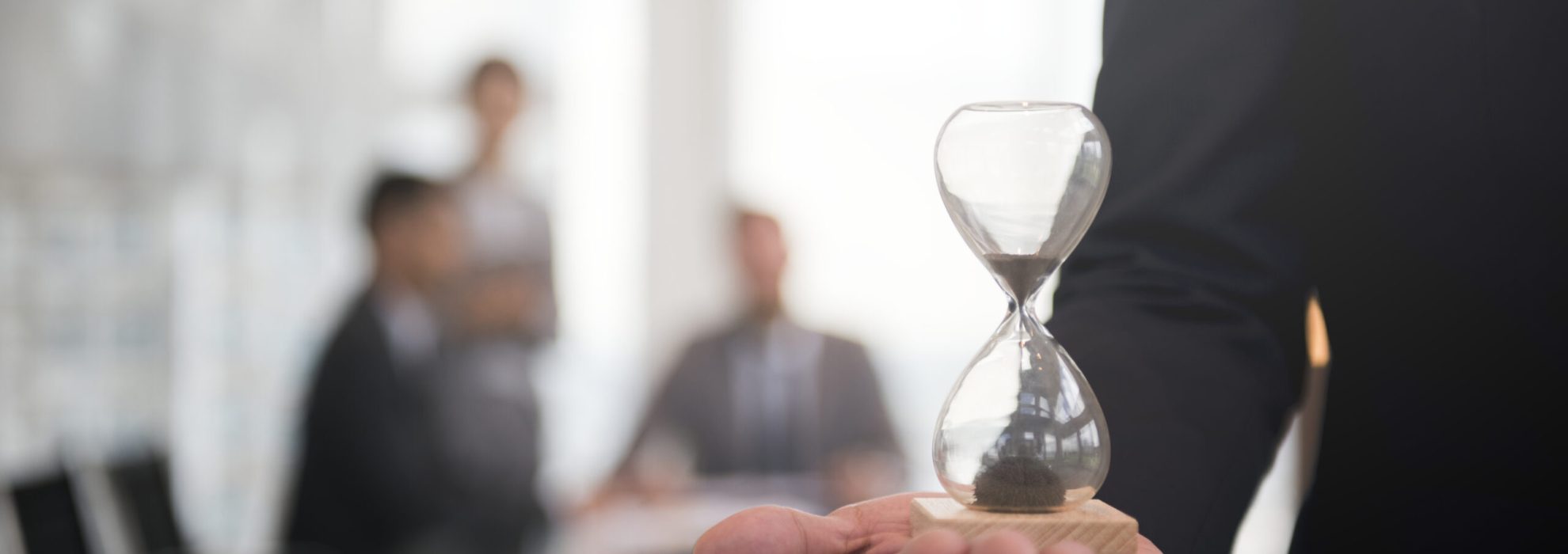 Businessman holding an hour glass, signifies the importance of being on time Businessman holding an hour glass, signifies the importance of being on time